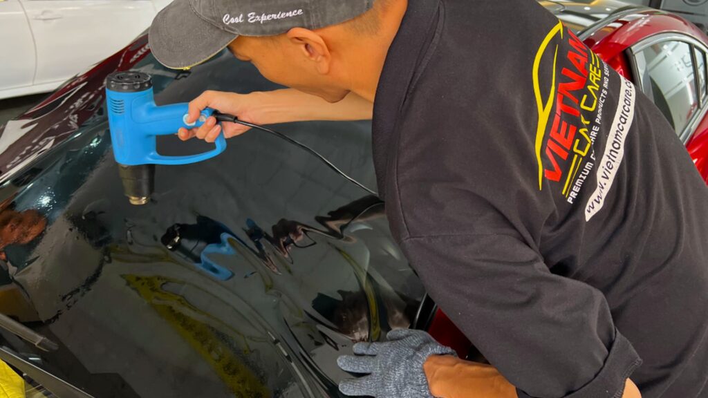 Kỹ thuật viên đang sấy kính sau khi dán phim cách nhiệt ô tô.